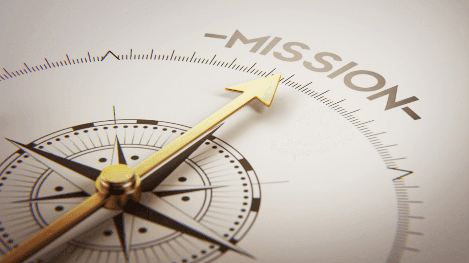 Close-up of a compass with a golden needle pointing towards the word 'MISSION'.