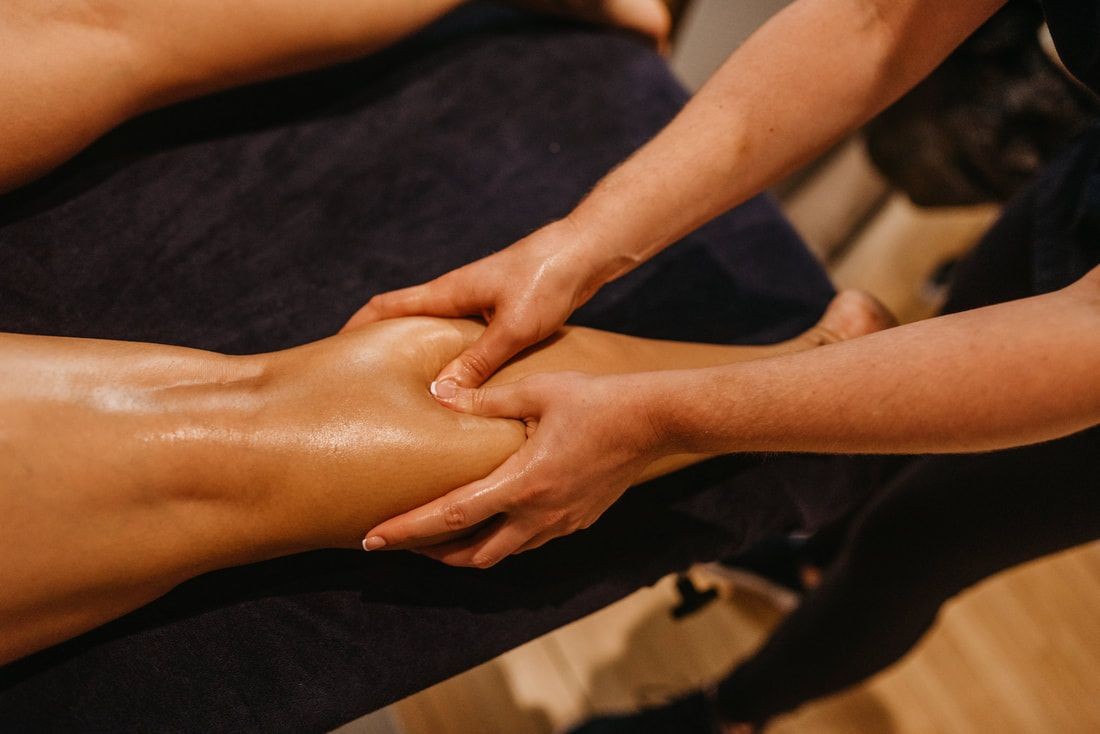 Close-up of a person receiving a calf massage with hands applying pressure to the lower leg.