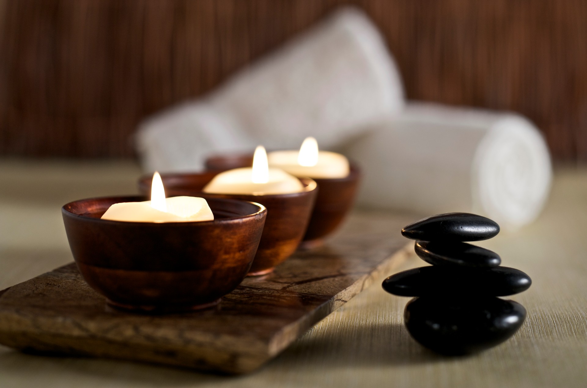 Lit candles and black massage stones in Zen spa